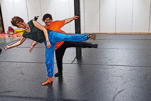 2 Tänzerinnen stehen hintereinander in der selben Pose mit angehobenem Bein. Das Bild sieht aus, als wäre es eine Zeichung