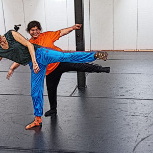 2 Tänzerinnen stehen hintereinander in der selben Pose mit angehobenem Bein. Das Bild sieht aus, als wäre es eine Zeichung