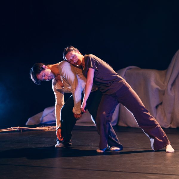 Two dancers on stage, a woman leaning on a man