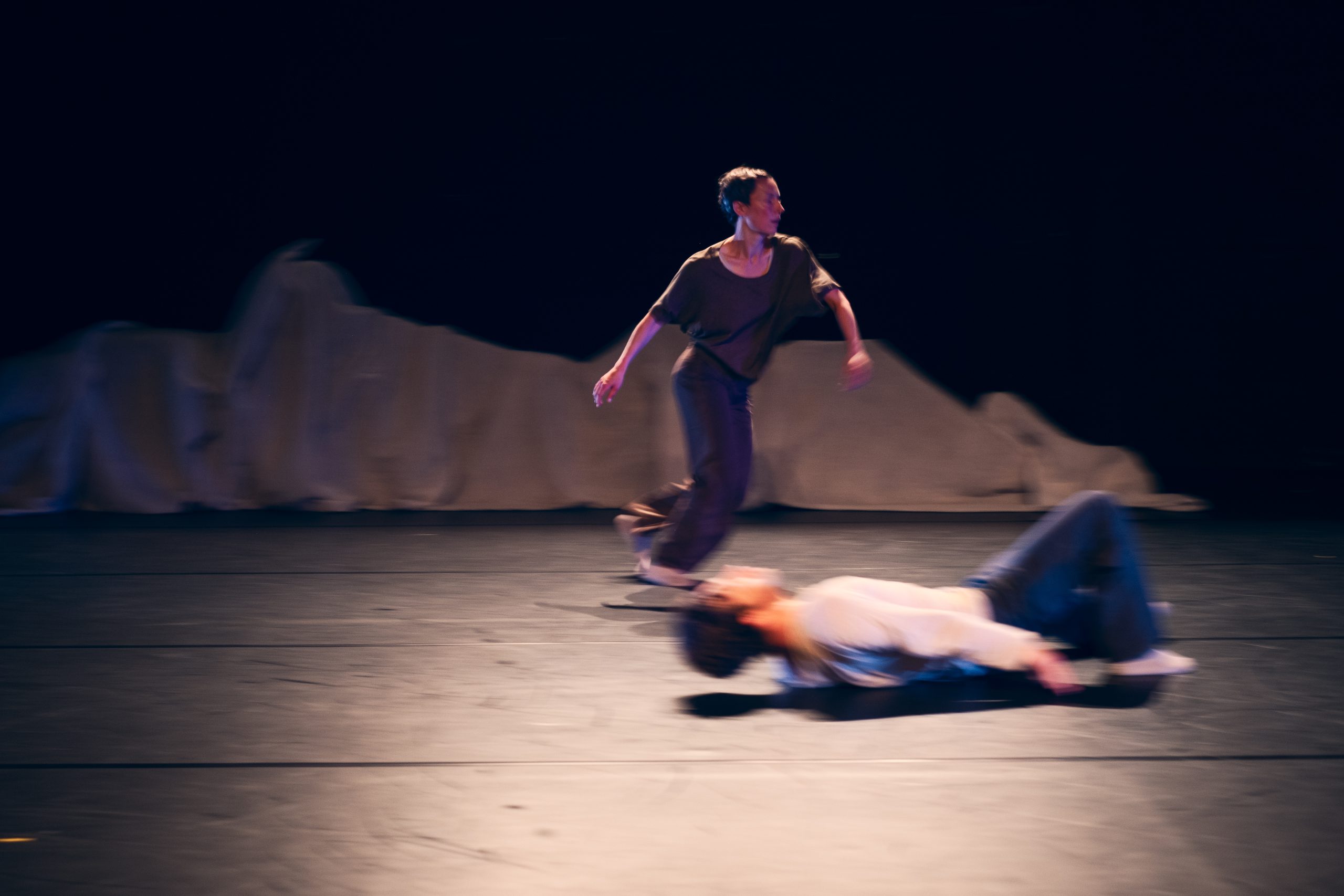 Eine Frau rennt, ein Mann legt sich auf den Boden. Eine dynamische Szene auf der Bühne.