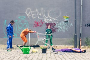 Tänzer:innen in bunten Kostümen vor einer Grafitti-Wand