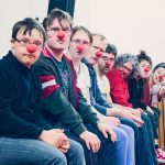 eine Gruppe von Menschen mit roten Nasen sitzt nebeneinander