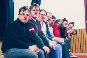 eine Gruppe von Menschen mit roten Nasen sitzt nebeneinander