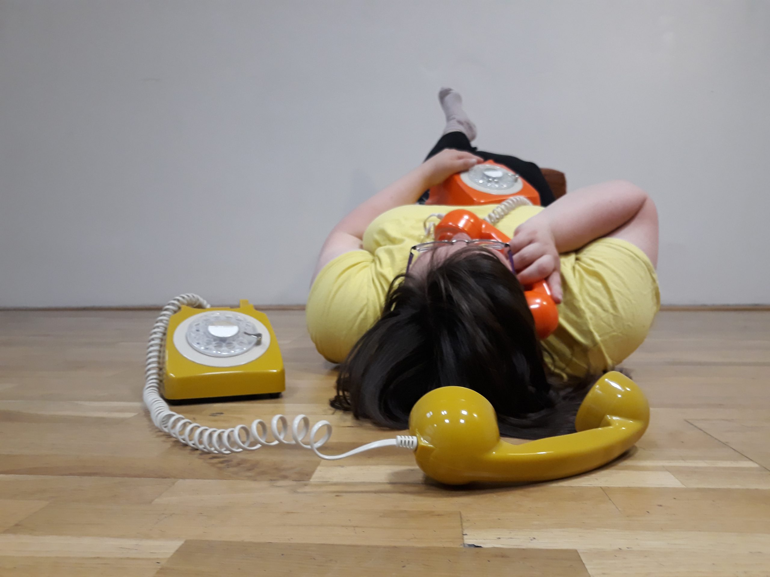 Isabel liegt am Boden mit einem Telefonhörer am Ohr