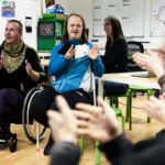 verschiedene Menschen sitzen im Raum und sprechen miteinander in Gebärdensprache