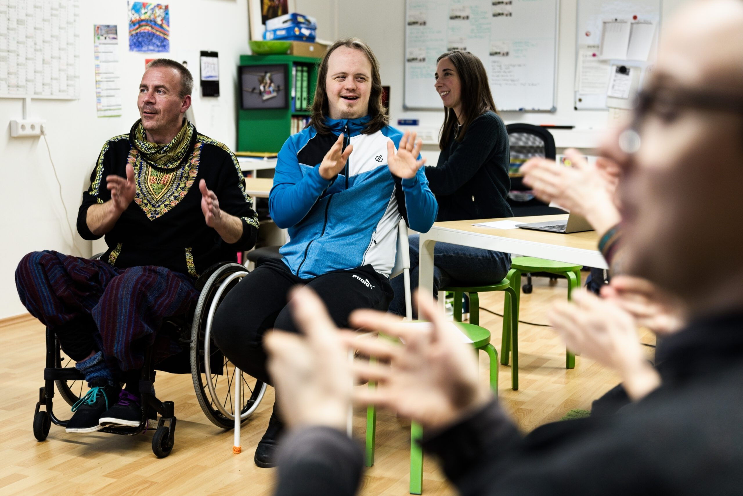 verschiedene Menschen sitzen im Raum und sprechen miteinander in Gebärdensprache