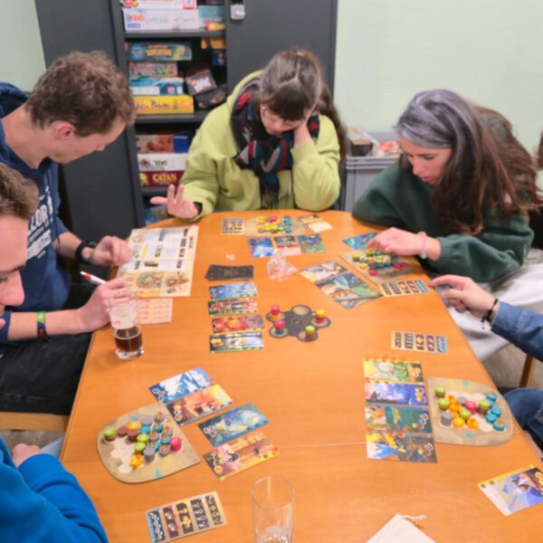 5 Menschen sitzen um einen Tisch und spielen ein Brettspiel