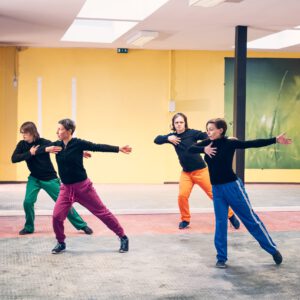 5 Tänzer:innen bewegen sich in einem bunten Raum
