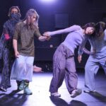 4 Tänzer:innen ziehen und schieben sich und lehnen aneinander