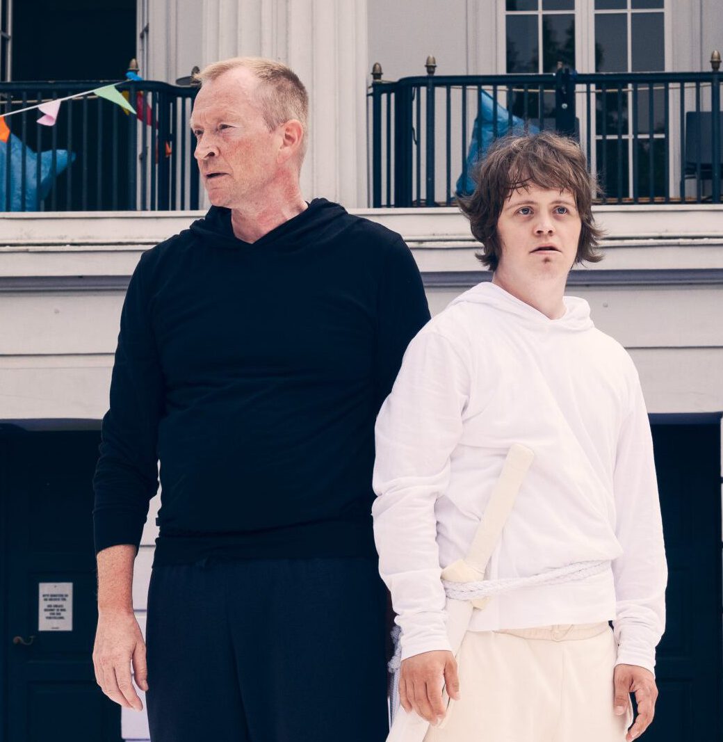 Two men standing side by side in front of a house